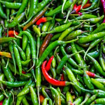 Heap of green and red chillis in retail vegetable super market for sale Stock Photos