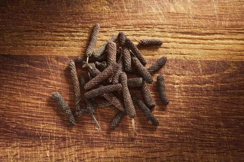 A heap of java long pepper on a wooden cutting board Stock-Fotos