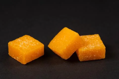 Heap of mango candy cubes on dark background. 스톡 사진