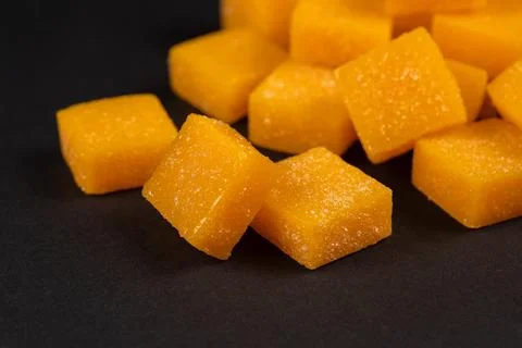 Heap of mango candy cubes on dark background. Stock Photos