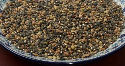 A heap of multicolored uncooked, dry roasted ricebean on a plate. Table spin. Stock Footage 279570076