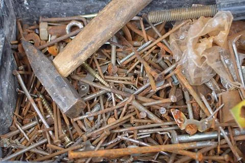 Heap of old rusty nails and screws on bottom of can with hammer Stock Photos