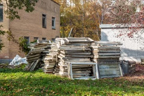 Heap of old wooden window frames with glass outdoors. Broken materials after  Stock Photos