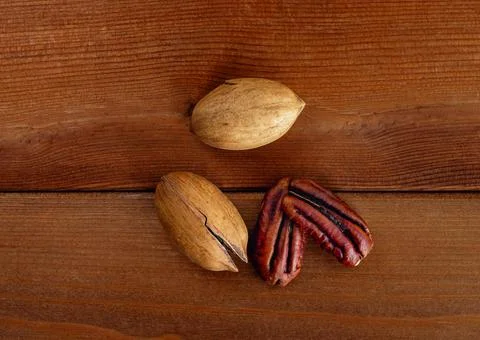 Heap of pecans in shell and decorticated peeled nut on wooden table Stock Photos