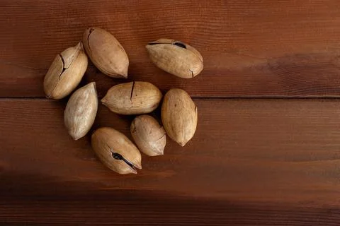 Heap of pecans in shell on wooden table Stock Photos
