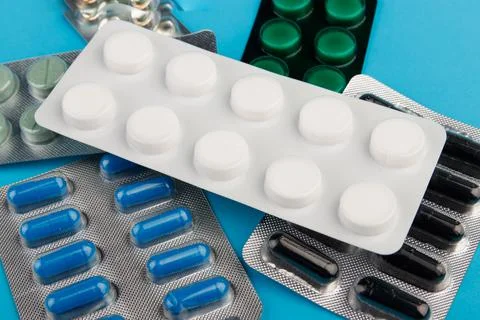 Heap of pills in blister packaging on blue desk. Concept of healthcare, drug Stock Photos