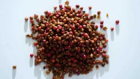 Heap of pink peppercorns on a white flat surface Stock Footage 333809710