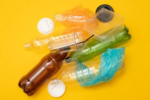 Heap of plastic disposable packaging and disposable tableware on yellow backg Stock Photos