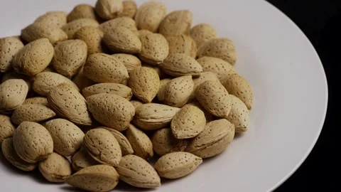 Heap of raw almonds in shells rotating on plate Stock Footage 328143129