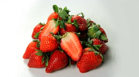 A heap of strawberries with leafs rotating on white table 4K. 動画素材 62274447