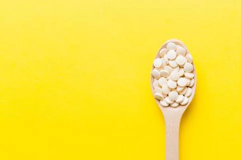 Heap of white pills on colored background. Tablets scattered on a table. Pile Stock Photos
