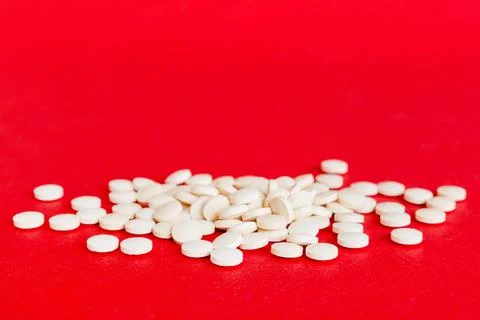 Heap of white pills on colored background. Tablets scattered on a table. Pile Stock Photos