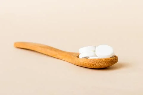 Heap of white pills on colored background. Tablets scattered on a table. Pile Stock Photos