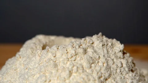 A heap of white wheat flour falling slowly on wooden board. Bakery process Stock Footage 111028858