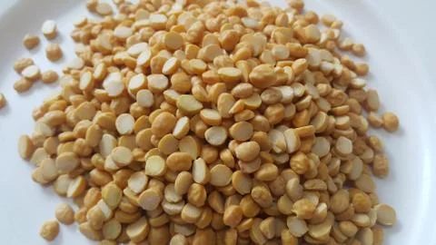 Heap of yellow split chickpeas in white plate background. Foto stock