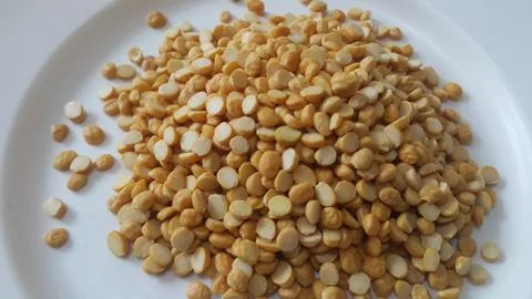 Heap of yellow split chickpeas in white plate background. 스톡 사진