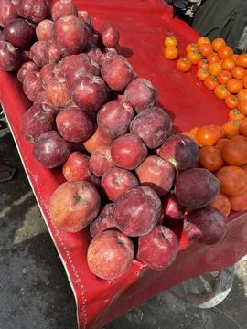 Heaps of Deep Red Apples and Orange Persimmons at Market Stock Photos