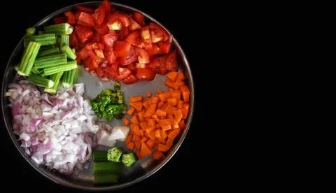 Heaps of different cut vegetables isolated on black background. Top view. Stock Photos