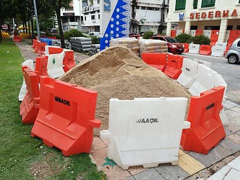 Heaps of sand and construction tools on the side of the road Stock Photos