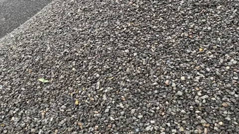 Heaps of small pebbles on wet ground near puddle Stock Footage 313475952