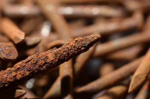 Heaps of used nails made of rusty iron material are brown mixed with black sp Stock Photos