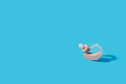 Hearing aid on blue background under hard light Stock Photos