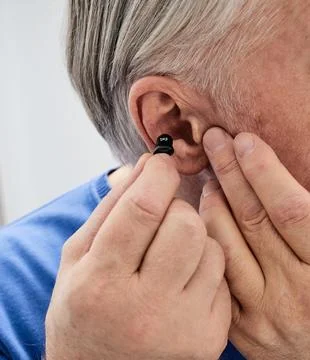 Hearing aid in the ear of elderly man, close-up. ITC hearing aid for hear tre Foto stock
