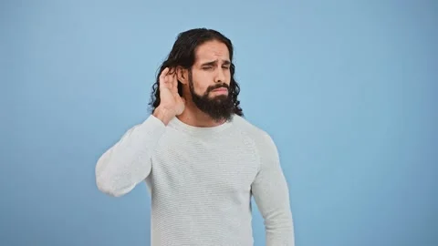 Hearing problem. Studio shot of bearded man trying to hear you, putting hand to Video stock 143910341