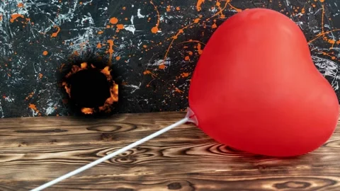 Heart balloon pops with fire effects and reveals dark hole in backdrop 스톡 동영상 342831692
