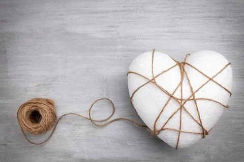 Heart bound by a string on grey background Stock Photos