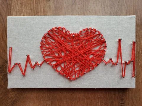 Heart crafted with vibrant red string art displaying heartbeat rhythm on te.. Stock Photos