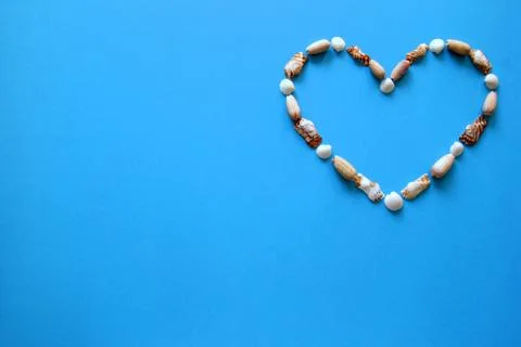 A heart from different seashells on the blue background for Valentine's Day. Stock Photos