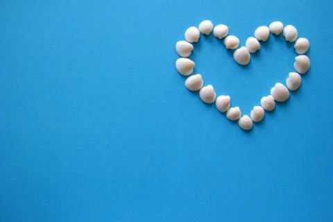 A heart from different seashells on the blue background for Valentine's Day. Stock Photos