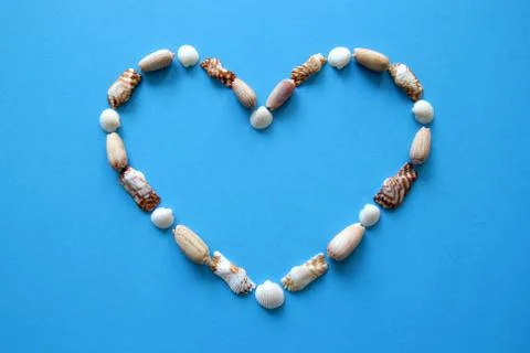A heart from different seashells on the blue background for Valentine's Day. Foto stock