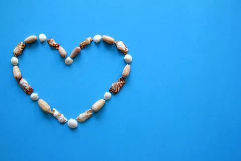 A heart from different seashells on the blue background for Valentine's Day. Stock Photos