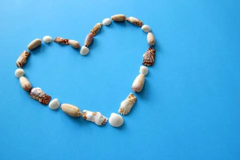 A heart from different seashells on the blue background for Valentine's Day. Stock Photos
