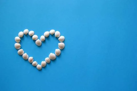 A heart from different seashells on the blue background for Valentine's Day. Stock Photos