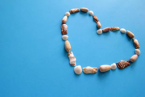 A heart from different seashells on the blue background for Valentine's Day. Stock Photos