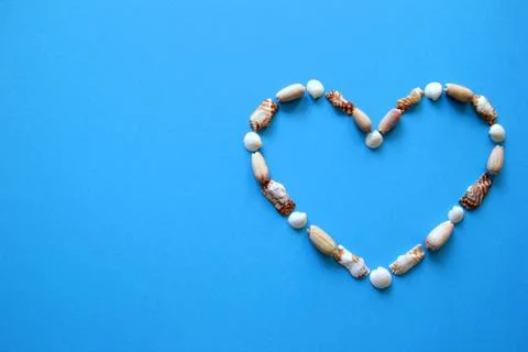 A heart from different seashells on the blue background for Valentine's Day. Stock Photos