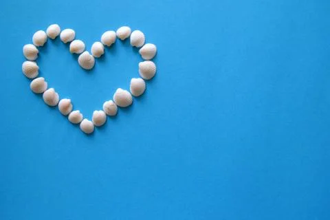 A heart from different seashells on the blue background for Valentine's Day. Stock Photos