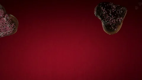 Heart donuts falling against red studio background Stock Footage 327050209