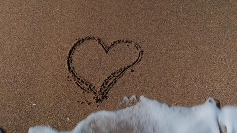 Heart drawn in the sand is washed away by the sea waves Stock Footage 345446381