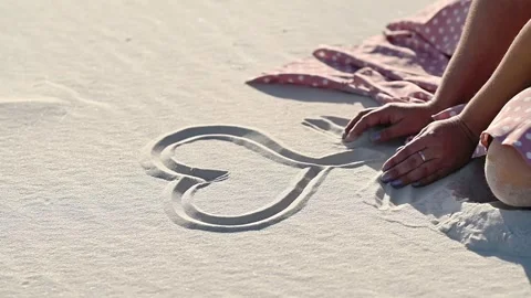 Heart drawn on smooth sand by human hands in sunlight. Stock Footage 330940565