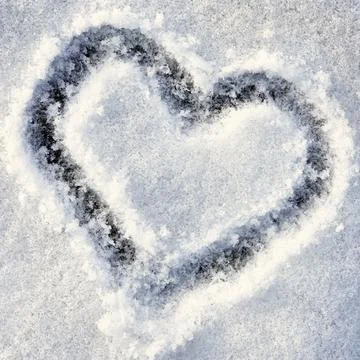A heart drawn into a thin layer of freshly fallen, grainy snow. Stock Photos