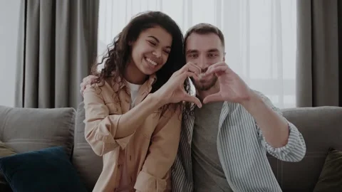 Heart gesture in the foreground. Out of focus, a couple in love sits on the Stock Footage 155358146