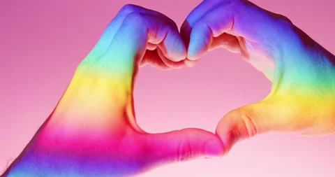 Heart Gesture of Two Hands in Rainbow Light over Pink Background in slow motion Stock Footage 347957872