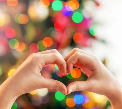 Heart from the hands in front of christmas tree Stock Photos