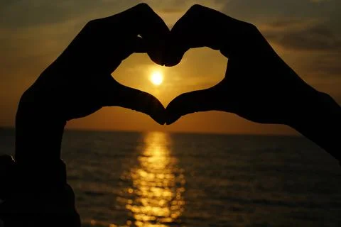 Heart from hands at sunset Stock Photos
