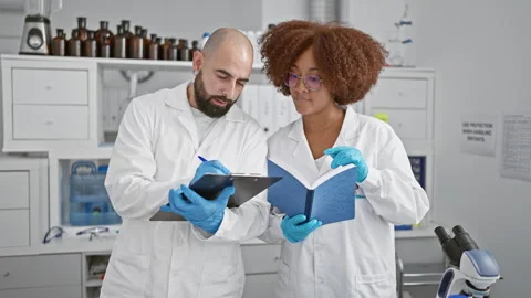 In the heart of the lab, two resolute scientists, checklist in hand, delve .. Stock Footage 268567886