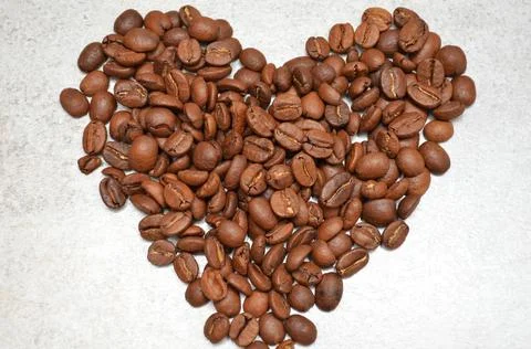 The heart is lined with coffee beans on the table. Stock Photos